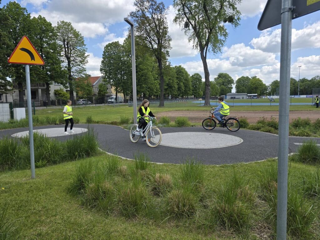 Zdjęcie przedstawia grupę młodzieży podczas zajęć w miasteczku ruchu drogowego