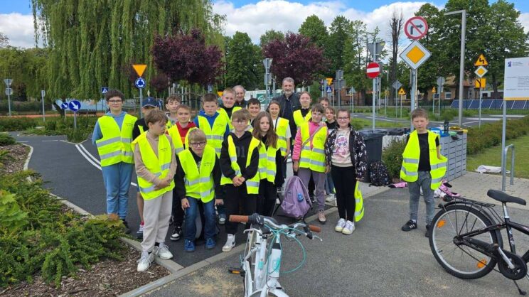 Zdjęcie przedstawia grupę młodzieży podczas zajęć w miasteczku ruchu drogowego
