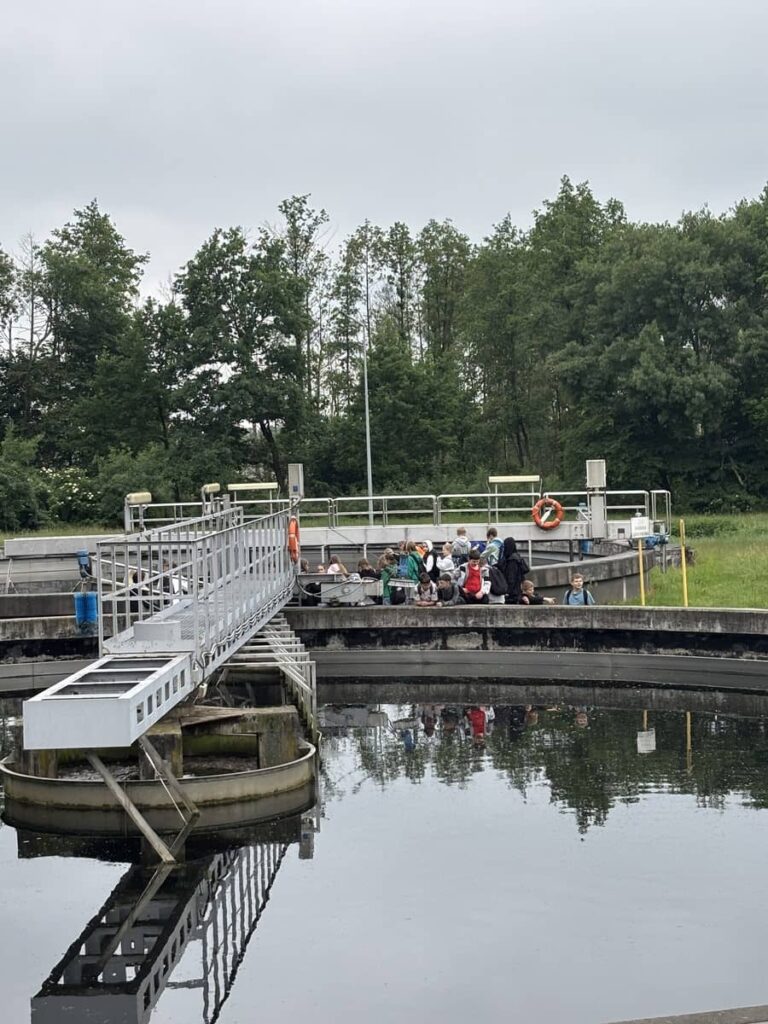 Zdjęcie przedstawia grupę młodzieży na terenie oczyszczalni ścieków w Pleszewie