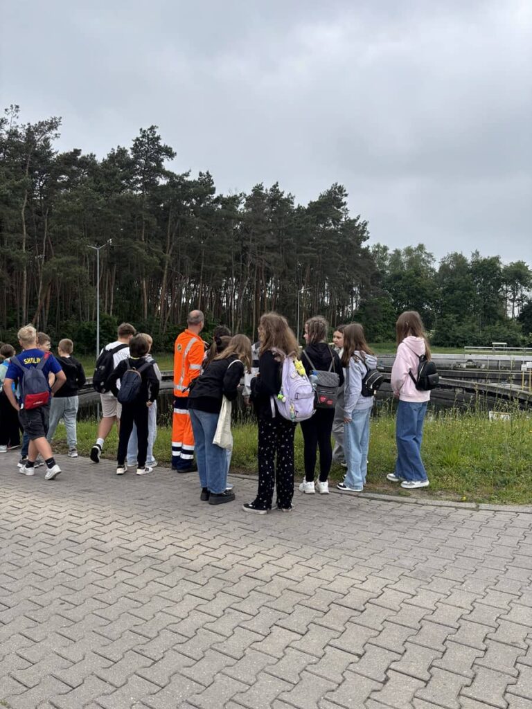 Zdjęcie przedstawia grupę młodzieży na terenie oczyszczalni ścieków w Pleszewie