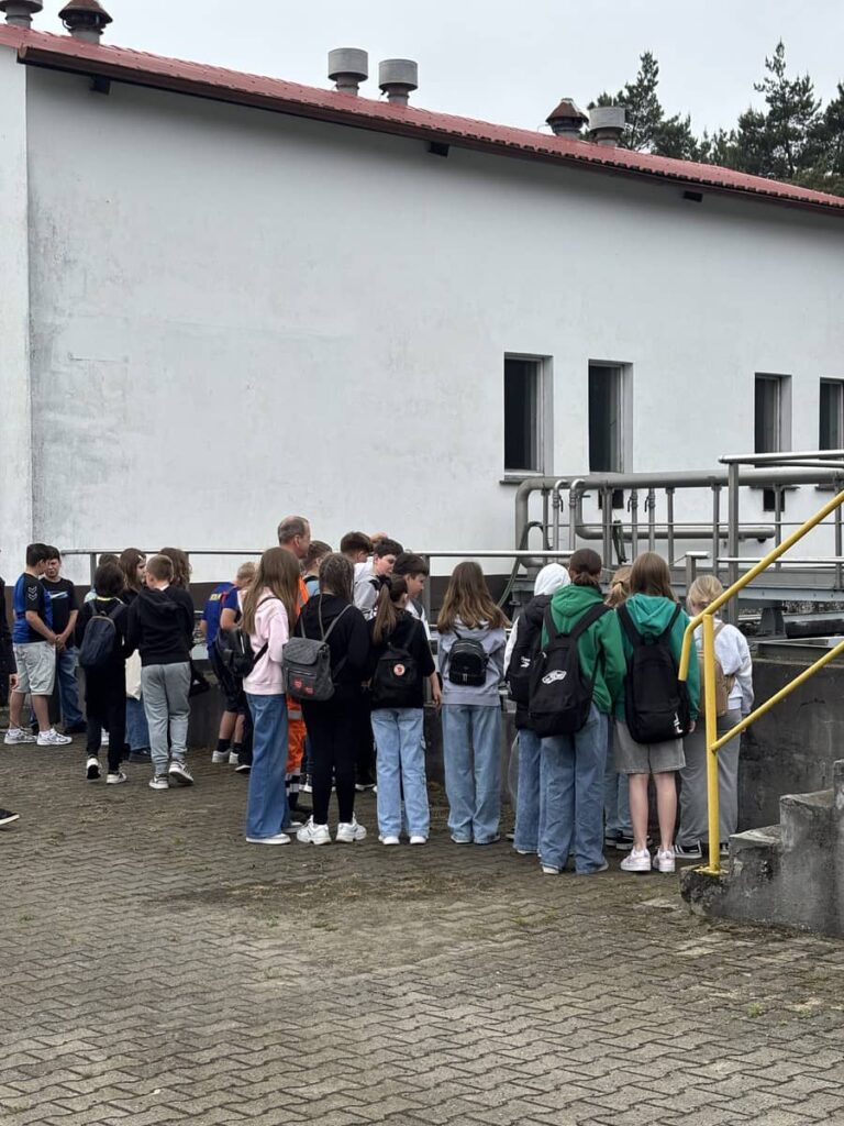 Zdjęcie przedstawia grupę młodzieży na terenie oczyszczalni ścieków w Pleszewie
