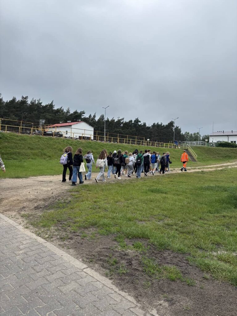 Zdjęcie przedstawia grupę młodzieży na terenie oczyszczalni ścieków w Pleszewie
