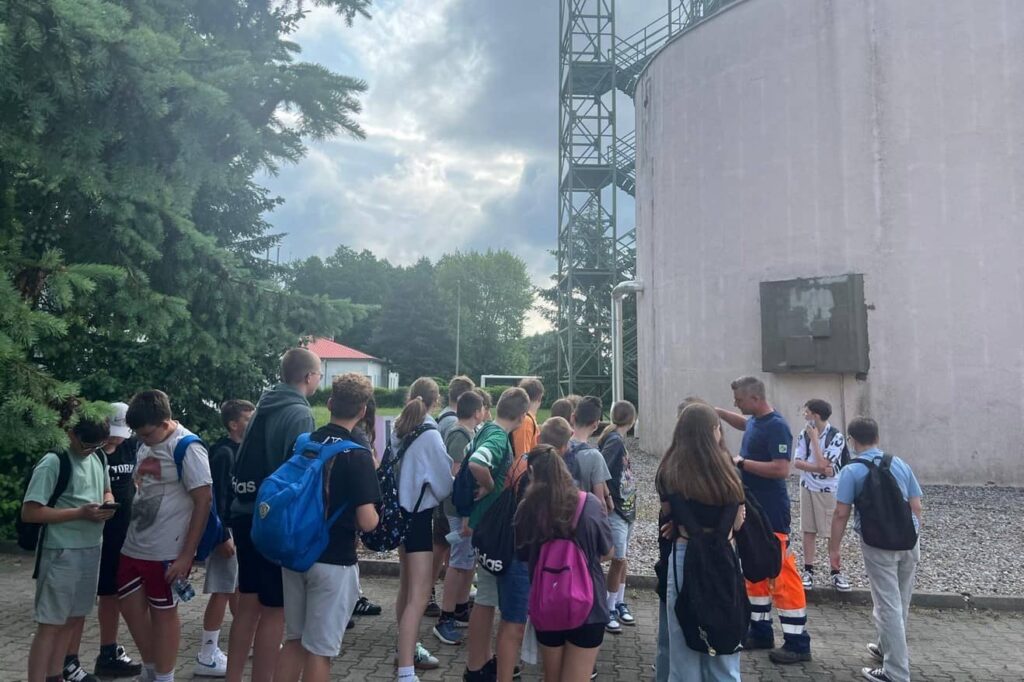 Zdjęcie przedstawia grupę młodzieży na terenie oczyszczalni ścieków w Pleszewie
