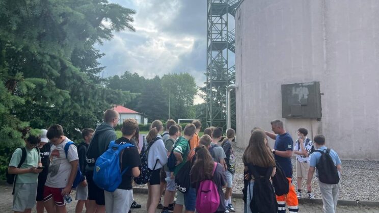 Zdjęcie przedstawia grupę młodzieży na terenie oczyszczalni ścieków w Pleszewie